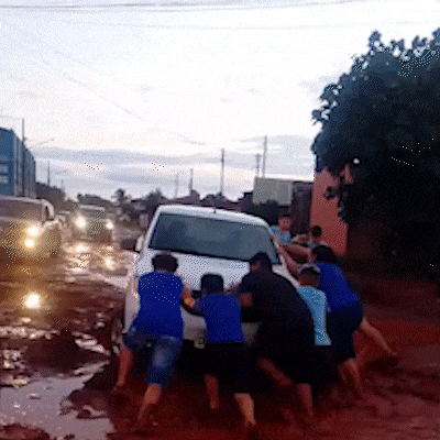 Crianças ajudando motorista a sair de atoleiro em Campo Grande