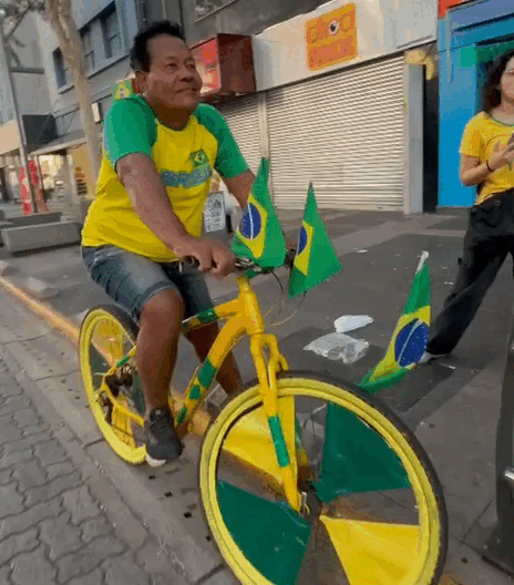 Pintor atrai olhares com bicicleta verde e amarela na Copa